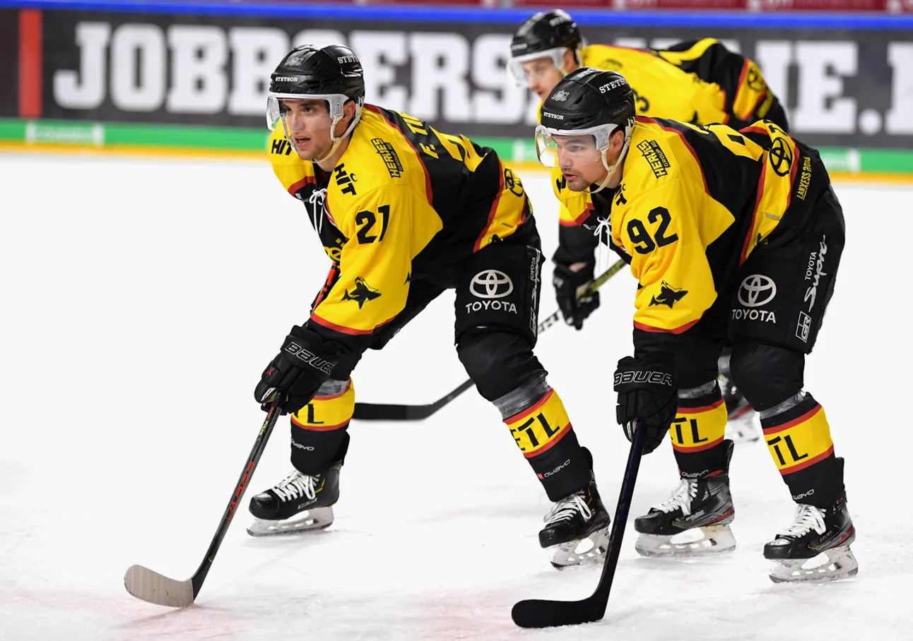 Two ice hockey players in yellow and black jerseys with numbers 21 and 92 on the ice, focused on the game.