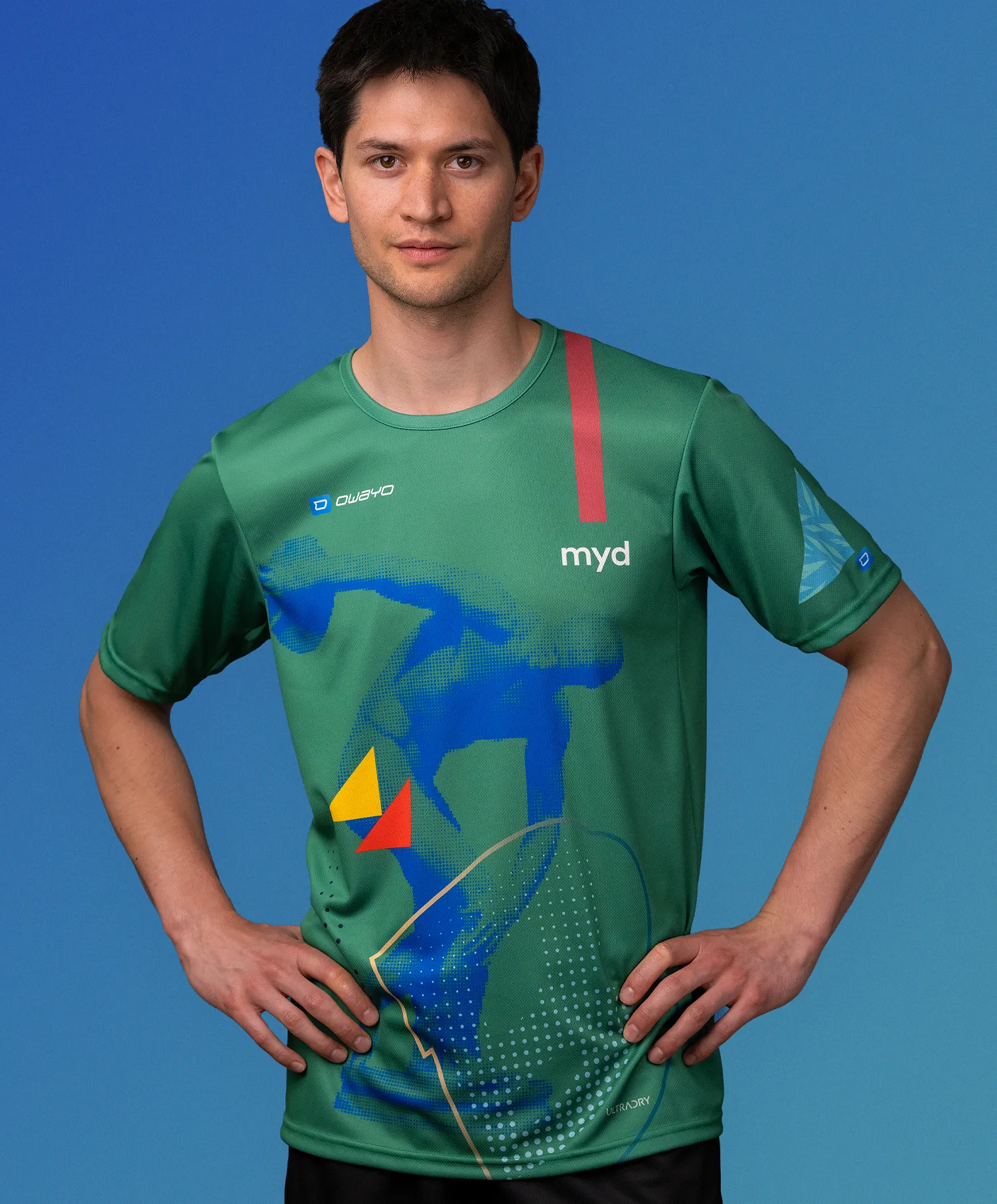A man wearing a green customized sportswear shirt from owayo featuring a blue, yellow, and red graphic design and the word 'myd' on the chest.