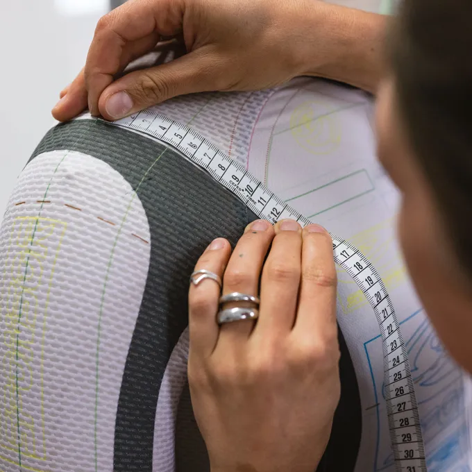 A person measures the upper arm of a custom-made sportswear garment from owayo, which is marked with pattern lines.
